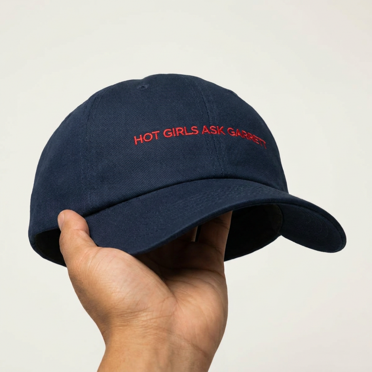 Hot Girls Ask Garrett embroidered dad cap held in hand